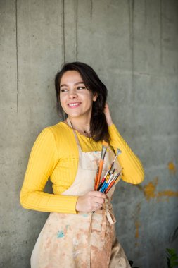 Çatı katında boya lekeleri olan önlüklü genç ve güzel bir bayan sanatçı.