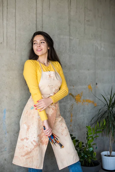 Ung vacker dam konstnär i förkläde med färg fläckar i hennes loft konstnärlig studio — Stockfoto