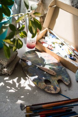 Sanatçılar stüdyosunun zemininde boya fırçaları ve çeşitli boyalar