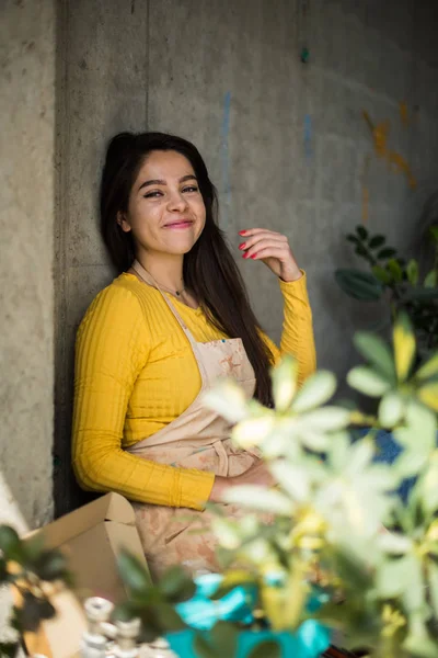 Junge schöne Künstlerin in Schürze mit Farbflecken auf dem Boden in ihrem Atelier — Stockfoto