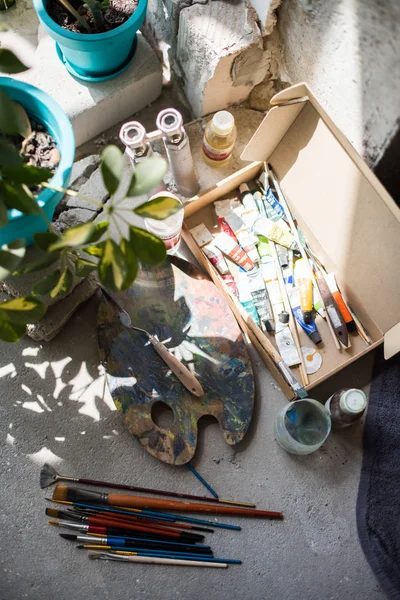 Sanatçılar stüdyosunun zemininde boya fırçaları ve çeşitli boyalar — Stok fotoğraf