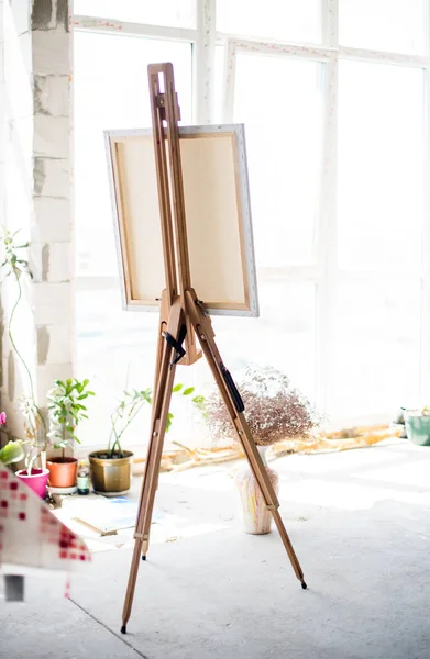 Easel com tela de pé em estúdio artístico vazio — Fotografia de Stock