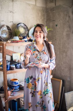 Güzel bayan sanatçı stüdyosunda ayakta, yaratıcı iş sahibi