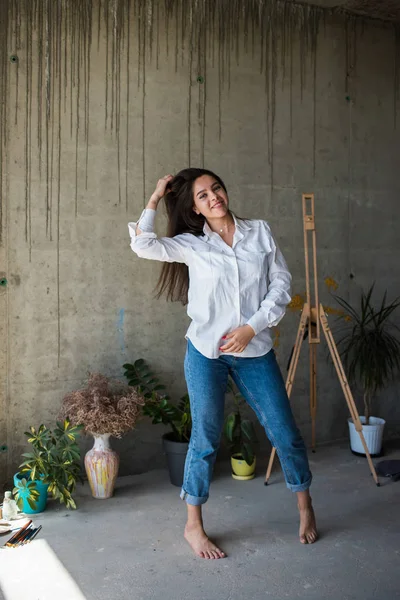 Mooie jonge dame kunstenaar in wit overhemd dansen blootsvoets in haar Boheemse artistieke Studio loft — Stockfoto