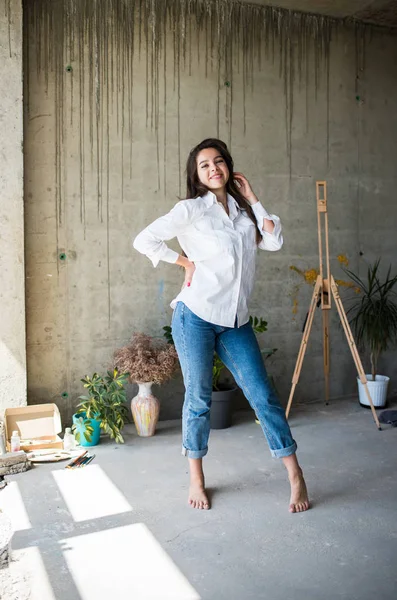 Mooie jonge dame kunstenaar in wit overhemd dansen blootsvoets in haar Boheemse artistieke Studio loft — Stockfoto