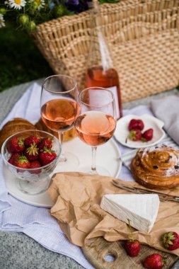 Şehir parkında çim üzerinde çilek, peynir ve gül şarabı ile güzel yaz piknik