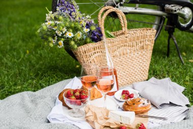 Şehir parkında çim üzerinde çilek, peynir ve gül şarabı ile güzel yaz piknik