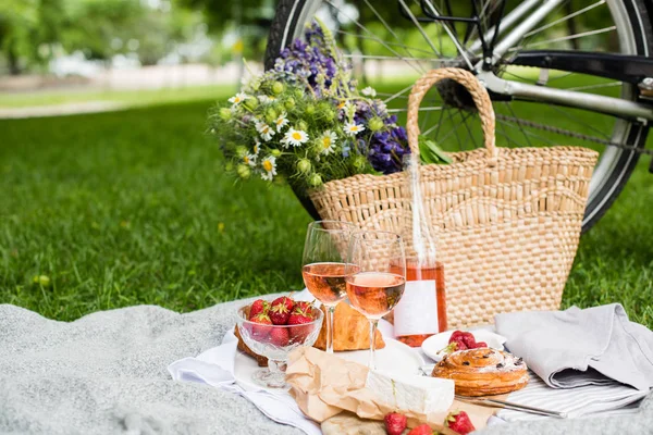 Bellissimo picnic estivo con fragole, formaggio e vino rosato sul prato nel parco cittadino — Foto Stock