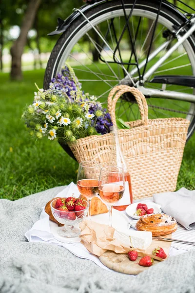 Beautiful summer picnic with strawberries, cheese and rose wine on the lawn in the city park