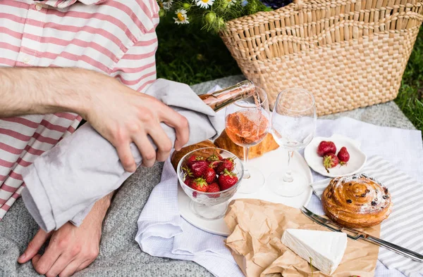 Чоловік наливає трояндове вино в келихи, літній пікнік — стокове фото