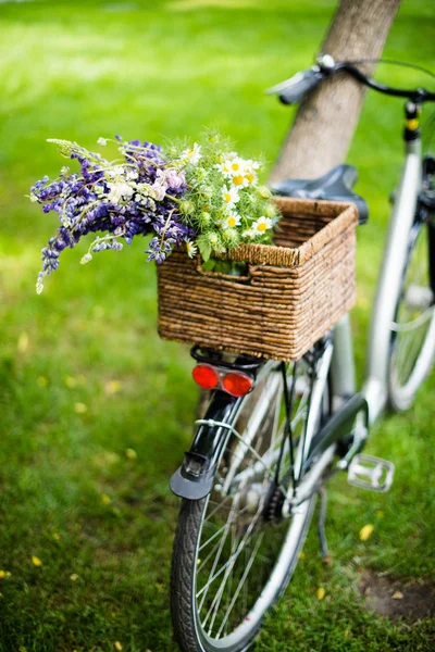 Nueva bicicleta de ciudad con ramo de flores en canasta de mimbre — Foto de Stock