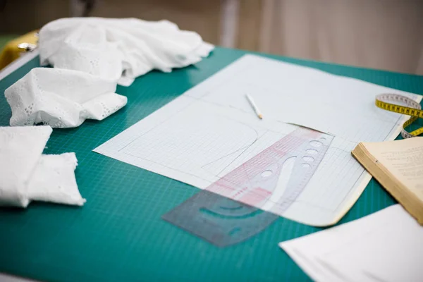 Herramientas, patrones y muestras de tela en la mesa de coser en el taller de sastrería —  Fotos de Stock