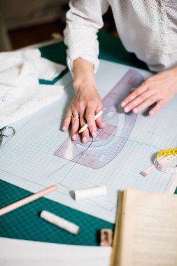 Atölyesinde çalışan bayan terzinin elleri, dikiş masasında ki alet ve kumaş örnekleri