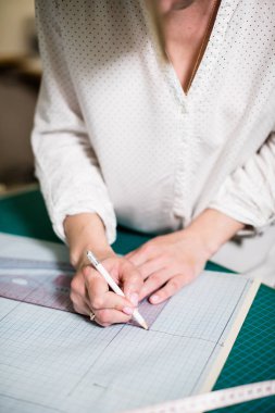 Atölyesinde çalışan bayan terzinin elleri, dikiş masasında ki alet ve kumaş örnekleri