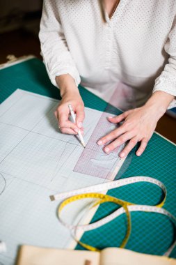 Atölyesinde çalışan bayan terzinin elleri, dikiş masasında ki alet ve kumaş örnekleri