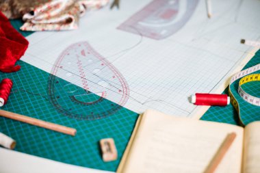 Terzi atölyesinde dikiş masasında aletler, desenler ve kumaş örnekleri