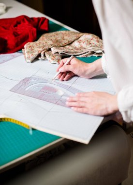 Atölyesinde çalışan bayan terzinin elleri, dikiş masasında ki alet ve kumaş örnekleri