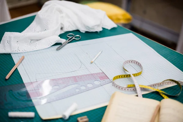 Herramientas, patrones y muestras de tela en la mesa de coser en el taller de sastrería — Foto de Stock