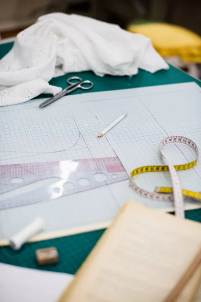 Herramientas, patrones y muestras de tela en la mesa de coser en el taller de sastrería —  Fotos de Stock