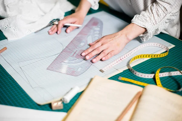 Manos de señora sastre trabajando en su estudio, herramientas y muestras de tela en la mesa de coser —  Fotos de Stock