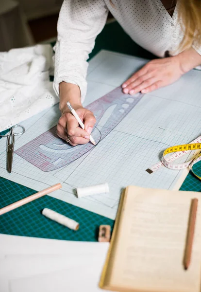 Manos de señora sastre trabajando en su estudio, herramientas y muestras de tela en la mesa de coser —  Fotos de Stock