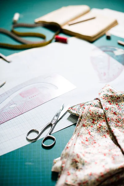 Инструменты, узоры и образцы ткани на швейном столе в швейной мастерской — стоковое фото