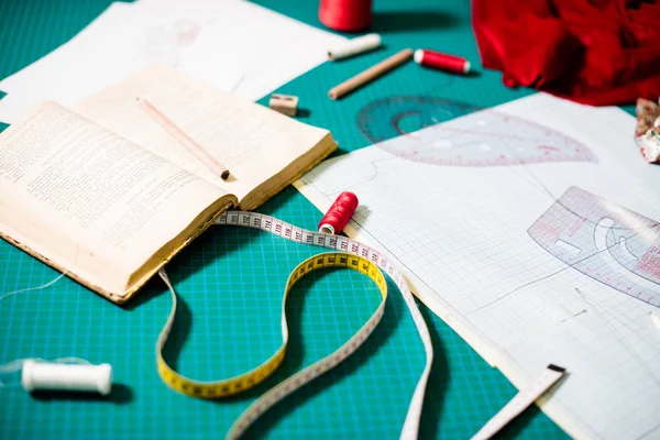 Herramientas, patrones y muestras de tela en la mesa de coser en el taller de sastrería —  Fotos de Stock