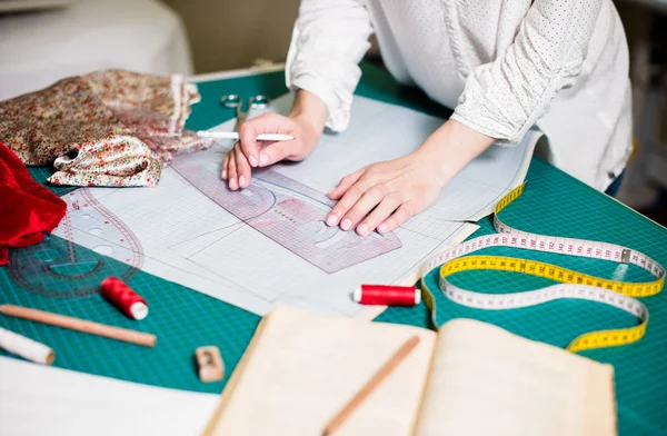 Manos de señora sastre trabajando en su estudio, herramientas y muestras de tela en la mesa de coser —  Fotos de Stock