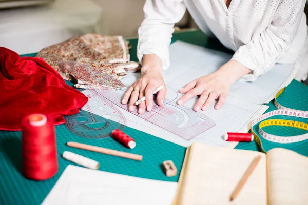 Manos de señora sastre trabajando en su estudio, herramientas y muestras de tela en la mesa de coser —  Fotos de Stock