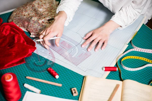 Manos de señora sastre trabajando en su estudio, herramientas y muestras de tela en la mesa de coser —  Fotos de Stock