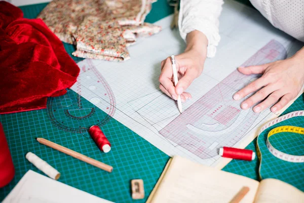 Handen van Lady Tailor werken in haar atelier, gereedschap en stof stalen op de naai tafel — Stockfoto