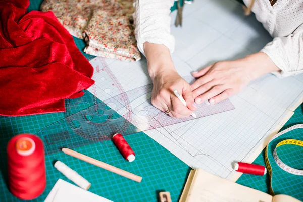Handen van Lady Tailor werken in haar atelier, gereedschap en stof stalen op de naai tafel — Stockfoto