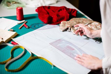 Atölyesinde çalışan bayan terzinin elleri, dikiş masasında ki alet ve kumaş örnekleri