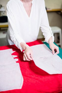 Atölyesinde çalışan bayan terzinin elleri, dikiş masasında ki alet ve kumaş örnekleri