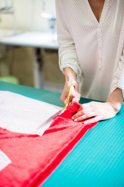 Atölyesinde çalışan bayan terzinin elleri, dikiş masasında ki alet ve kumaş örnekleri