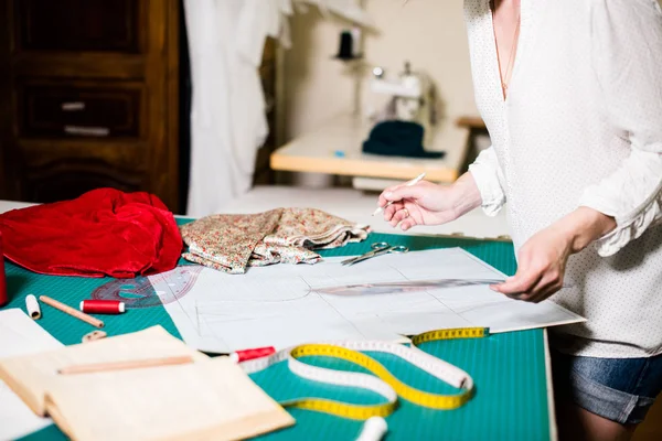 Händerna på Lady Tailor arbetar i hennes ateljé, verktyg och tygprover på sömnads bordet — Stockfoto