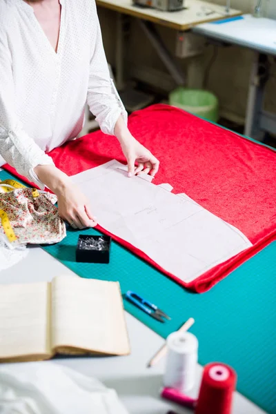 Händerna på Lady Tailor arbetar i hennes ateljé, verktyg och tygprover på sömnads bordet — Stockfoto