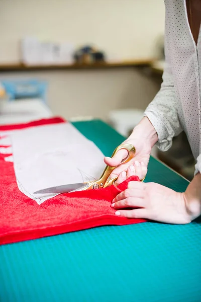 Manos de señora sastre trabajando en su estudio, herramientas y muestras de tela en la mesa de coser —  Fotos de Stock