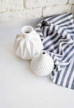 Beyaz arka plan üzerinde iki beyaz seramik vazo ve çizgili bez