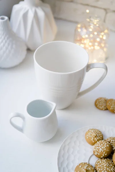 简单的白色杯子和一个奶油在白色桌子上与饼干 — 图库照片