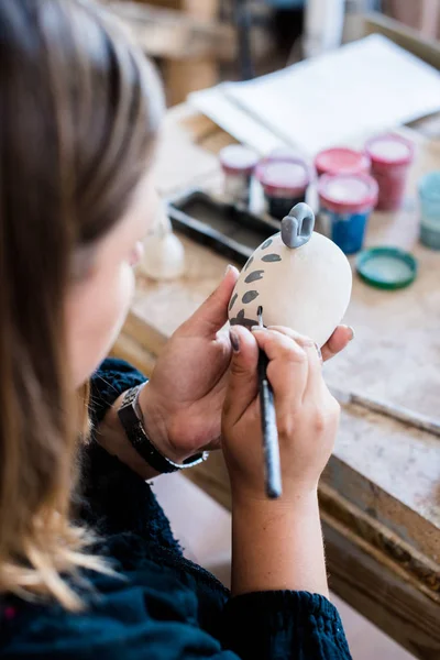 Lady ceramic artist working in her studio interior, womans hands painting objects