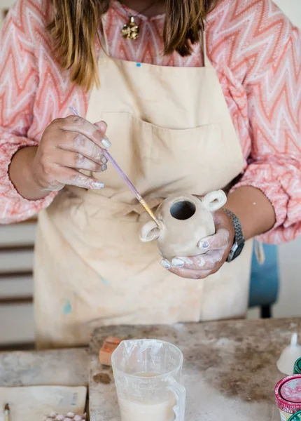 Lady ceramic artist working in her studio interior, womans hands painting objects