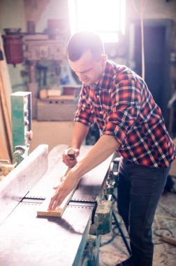 Genç yakışıklı doğrama onun marangozluk atölyesinde ahşap ile çalışan