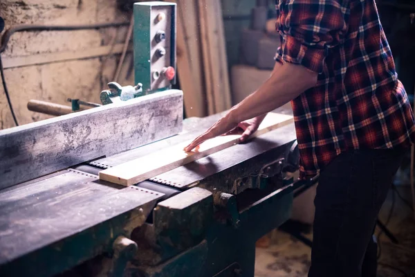 Joven carpintero guapo trabajando con madera en su taller de carpintería — Foto de Stock