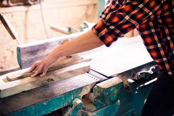 Joven carpintero guapo trabajando con madera en su taller de carpintería — Foto de Stock