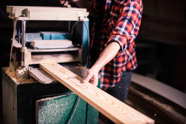 Jovem marceneiro bonito trabalhando com madeira em sua oficina de carpintaria — Fotografia de Stock