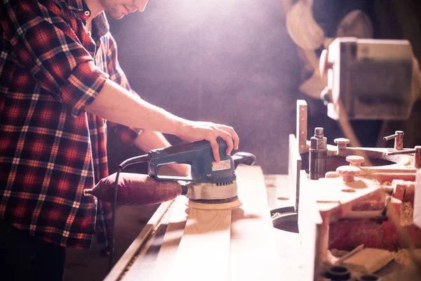 Joven carpintero guapo trabajando con madera en su taller de carpintería — Foto de Stock