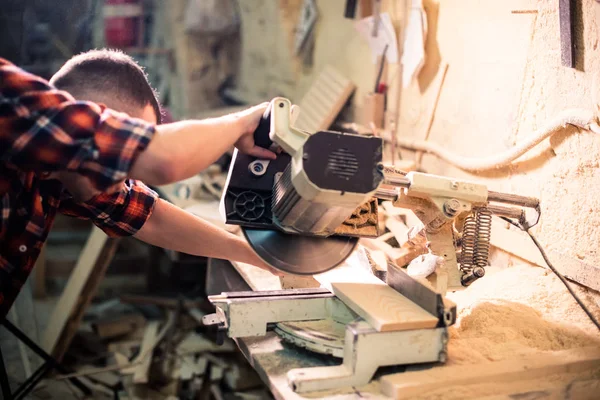 Joven carpintero guapo trabajando con madera en su taller de carpintería — Foto de Stock