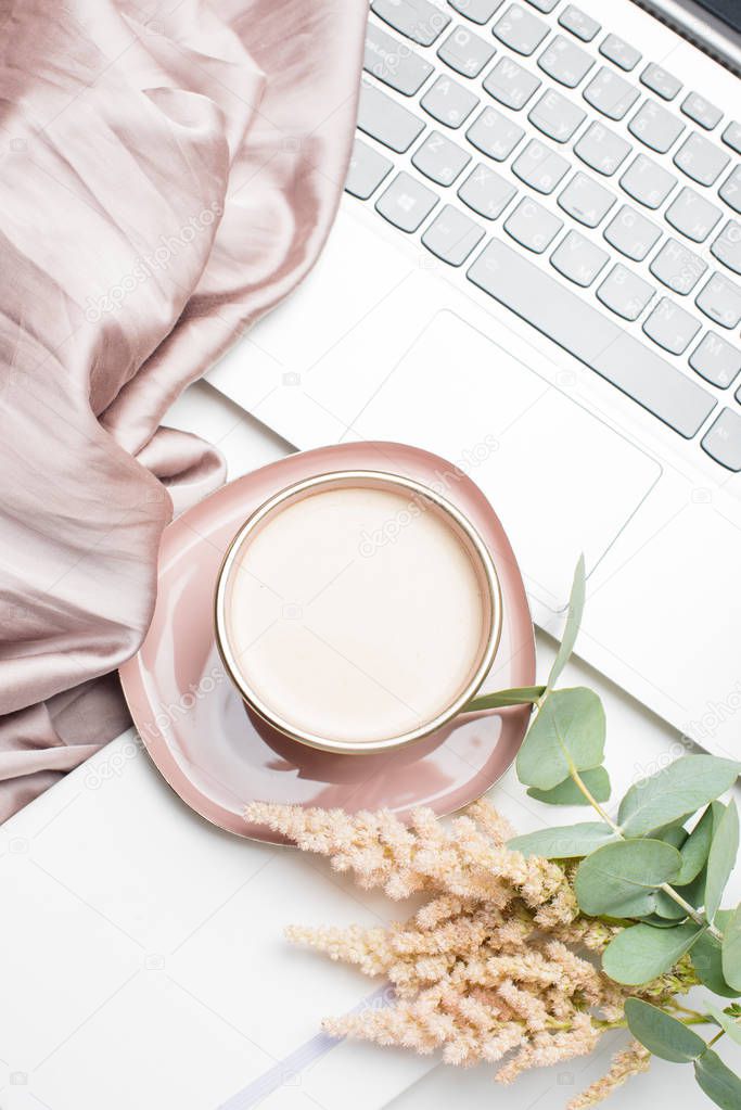 Beautiful enameled pink cup of coffee with blanket and laptop