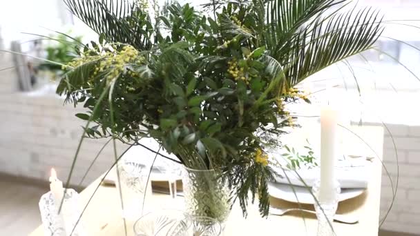 Bela decoração de mesa com buquê exótico de folhas e flores de mimosa, configuração de mesa de festa em casa — Vídeo de Stock